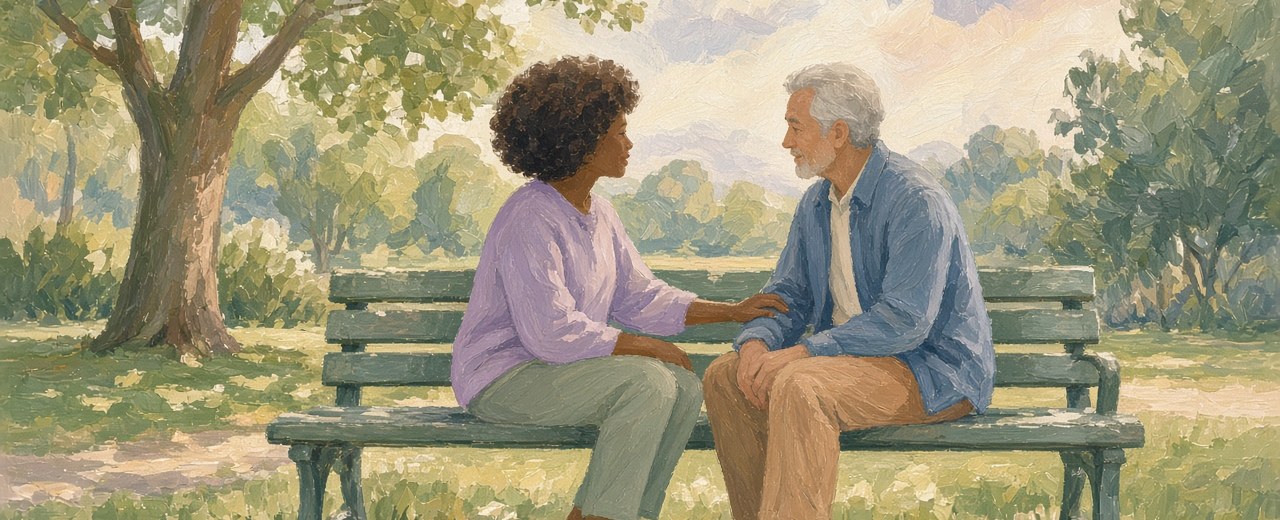 Two people talking calmly together on a park bench under soft trees.